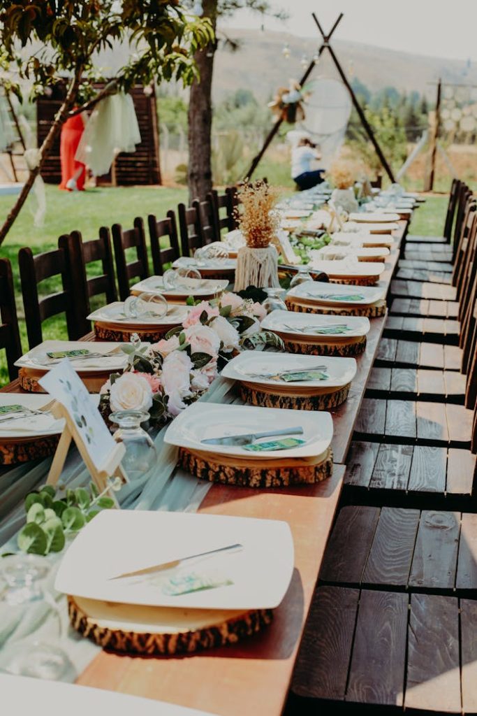 a-table-setting-for-a-rustic-wedding-theme-13534760 Beautiful rustic table setup for a wedding with wooden decor, plates, and floral arrangements outdoor setting.