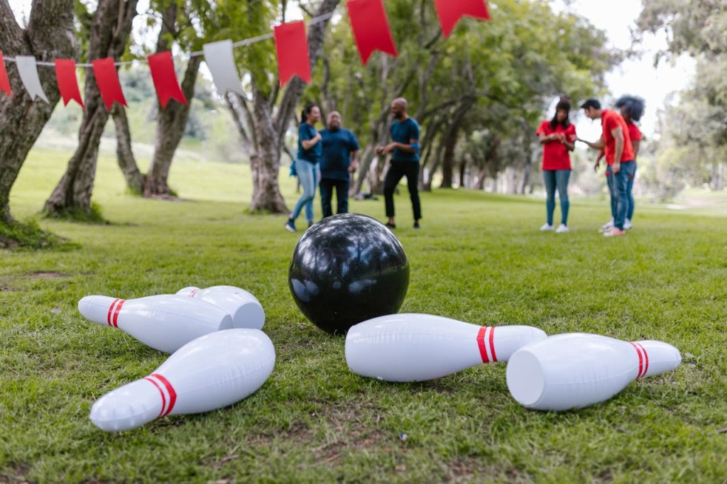 people-in-green-grass-field-7551782 A group of adults playing inflatable bowling for team building outdoors.