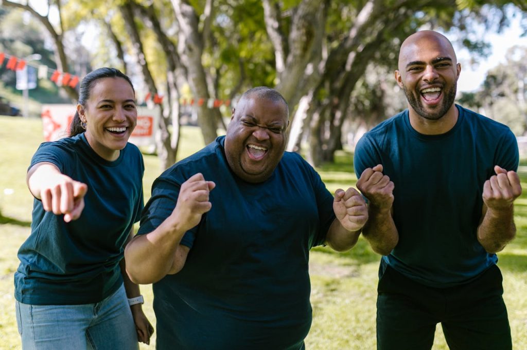 A diverse group of adults enjoying a successful outdoor team-building event in a park.